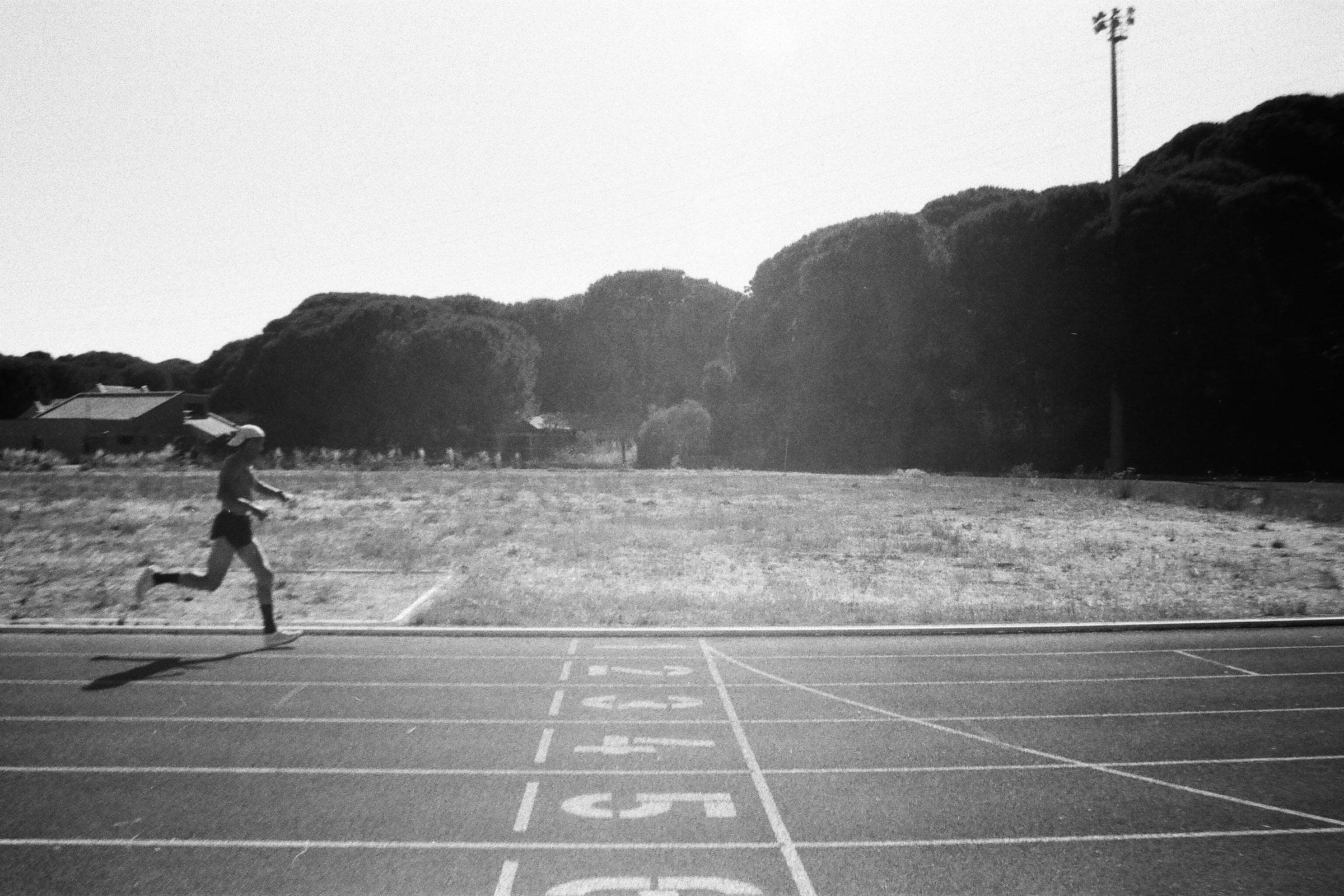 Una corredora en una pista de atletismo junto a las calles numeradas, en blanco y negro.